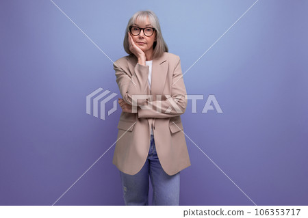 60s mature woman in business attire stands thoughtfully on a studio background with copy space 106353717