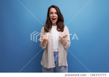 surprised pretty brunette young female adult in shirt and jeans on background with copy space surprised pretty brunette young female adult in shirt and jeans on background with copy space 106353773