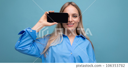 attractive confident blond girl holding a smartphone with a screen at the camera with a blank mockup attractive confident blond girl holding a smartphone with a screen at the camera with a blank mockup 106353782
