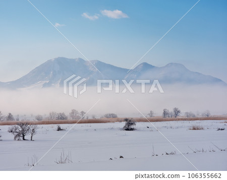 View of Mt. Kosha from the snowy fields of the Chikuma River in the morning mist 106355662