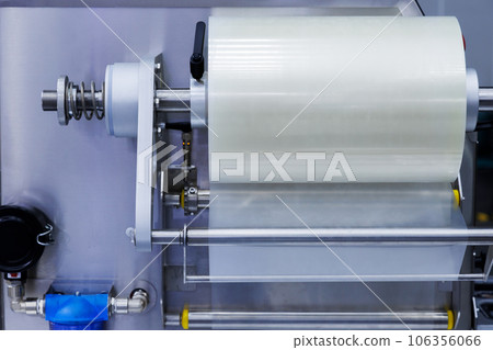 roll of plastic packaging film on the automatic packing machine in food product factory. industrial and technology concept. 106356066