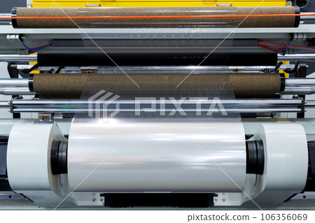 roll of plastic packaging film on the automatic packing machine in food product factory. industrial and technology concept. roll of plastic packaging film on the automatic packing machine in food product factory. industrial and technology concept. 106356069