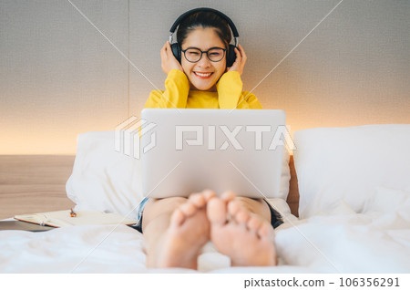 Asian woman enjoying listening music in headphones while quarantine herself at home. Conceptual of woman lifestyle. Asian woman enjoying listening music in headphones while quarantine herself at home. Conceptual of woman lifestyle. 106356291