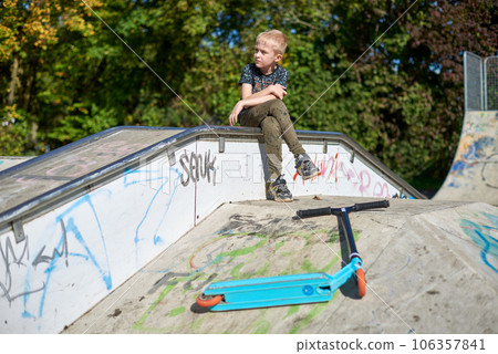 Child on kick scooter in park. Kids learn to skate roller board. Little boy skating on sunny summer day. Outdoor activity for children on safe residential street. Active sport for preschool kid. boy 106357841