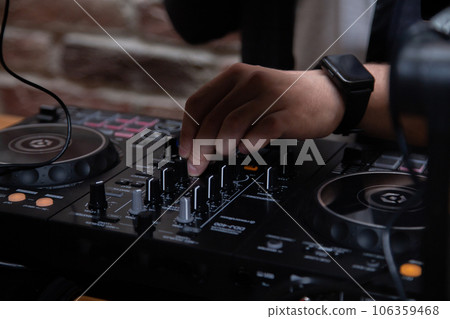 A DJ in a nightclub at the control panel adjusts the music. Music is playing, creating an atmosphere. High quality photo A DJ in a nightclub at the control panel adjusts the music. Music is playing, creating an atmosphere. High quality photo 106359468