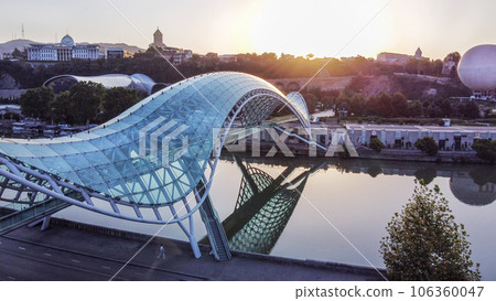 Sunrise in Georgian capital -Tbilisi , pedstrian bridge of Peace over Kura river and cityscape with President building in distance Sunrise in Georgian capital -Tbilisi , pedstrian bridge of Peace over Kura river and cityscape with President building in distance 106360047