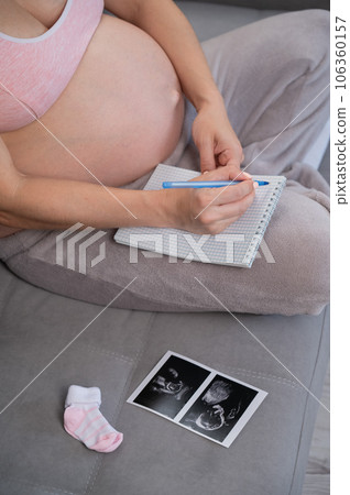 Pregnant woman takes notes in a notebook. Pregnant woman takes notes in a notebook. 106360157
