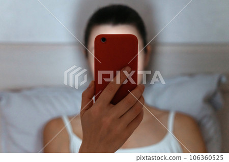 Woman on bed looking at smartphone late at night. Woman on bed looking at smartphone late at night. 106360525