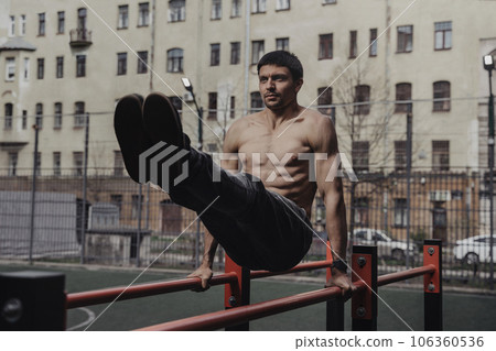 Young man doing parallel bars abdominal exercise. Young man doing parallel bars abdominal exercise. 106360536