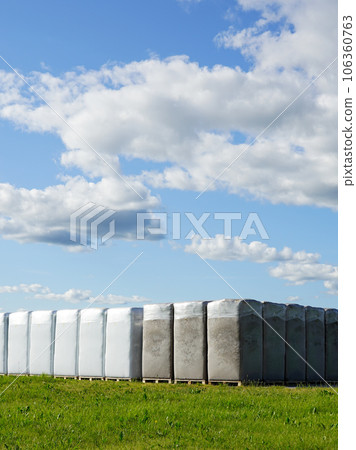 Peat extraction, many large bags of peat on the production area of a factory under a blue sky 106360763