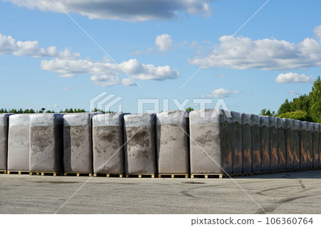 Peat extraction, many large bags of peat on the production area of a factory under a blue sky 106360764