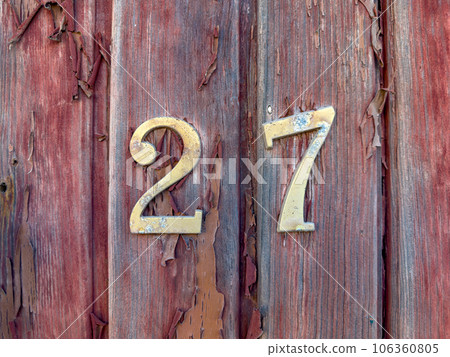 Number 27 on red painted old wooden wall. 106360805