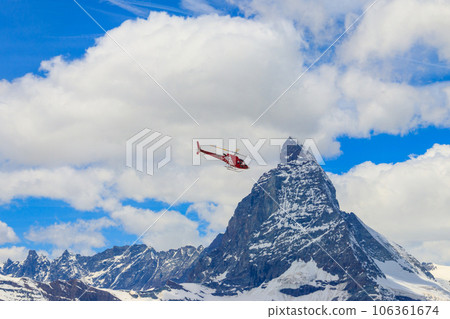 Helicopter flying over snowy Matterhorn peak, Switzerland 106361674