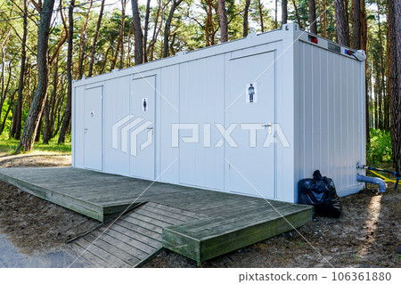 Modern public metal three toilet container with a wooden terrace in a seaside park Modern public metal three toilet container with a wooden terrace in a seaside park 106361880