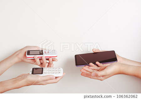 Hands offer an exchange of a push-button phone for a smartphone Hands offer an exchange of a push-button phone for a smartphone 106362062