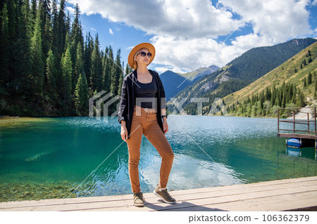 Tourist woman in brown hat posing on Kolsay lake in Kolsai Koldery gorge near Almaty, nature of Kazakhstan National Park in Central Asia 106362379