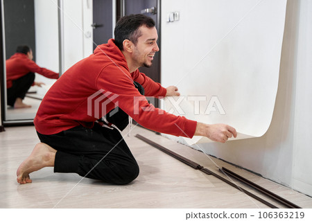 Repair the house with their own hands. The guy is ripping the old wallpaper off the wall 106363219