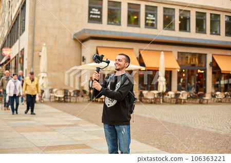 Tourist shoots a video with a gimbal in the street of the city 106363221