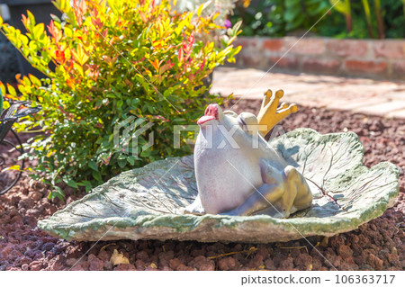 Garden and Home decoration of a green frog with golden crown sitting on a green leaf Garden and Home decoration of a green frog with golden crown sitting on a green leaf 106363717