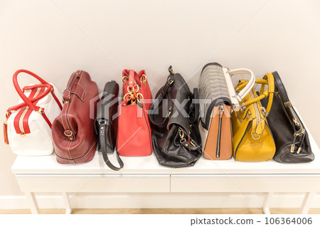 Collection of fashinable bags standing on a shelf in a row Collection of fashinable bags standing on a shelf in a row 106364006