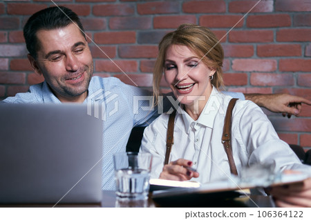 Happy business people working together on laptop in a restaurant Happy business people working together on laptop in a restaurant 106364122