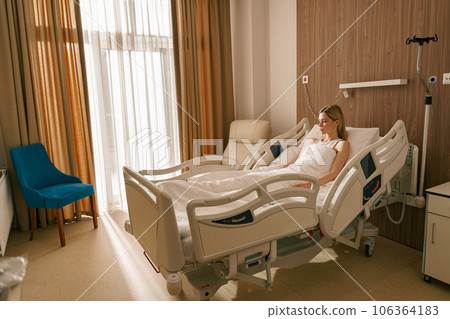 Woman patient lying on bed at modern hospital ward before surgery. Health care and medicine concept Woman patient lying on bed at modern hospital ward before surgery. Health care and medicine concept 106364183