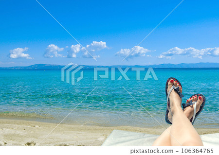 Woman wearing flip-flops laying on the sunbed near the ocean on a beach Woman wearing flip-flops laying on the sunbed near the ocean on a beach 106364765