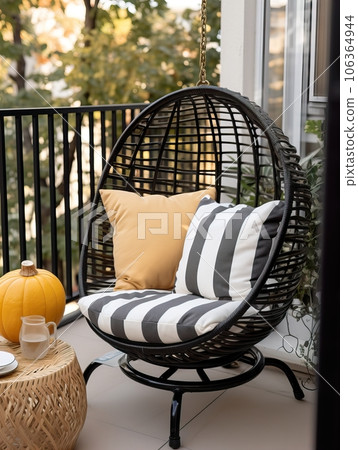 Cozy autumn balcony decor, warm fall city balcony decor with chair and pillows, pumpkins, yellow leaves and candles 106364944