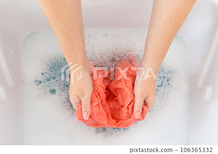 Female hands washing color clothes in sink Female hands washing color clothes in sink 106365332