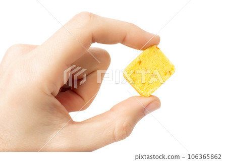 Yellow bouillon cube in hand. Isolate on a white background. 106365862