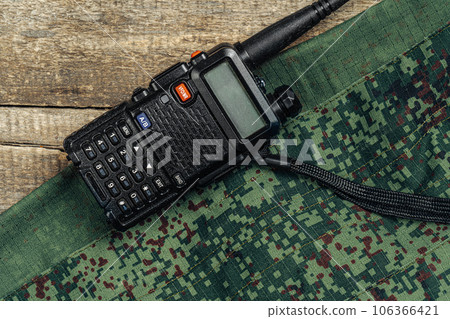 Walkie-talkie and military uniform on wooden surface 106366421