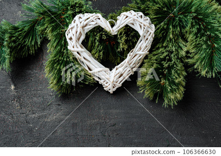 Fir tree branches with wooden heart on black Fir tree branches with wooden heart on black 106366630