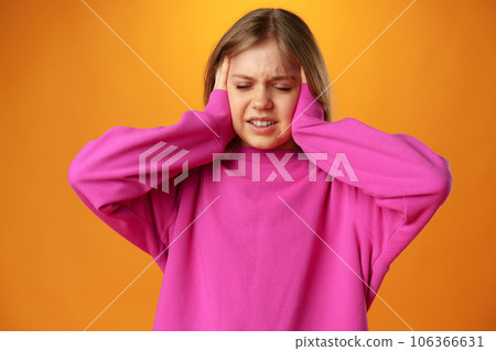 Teenage girl is touching her temples suffering headache on yellow background Teenage girl is touching her temples suffering headache on yellow background 106366631