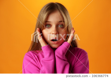 Surprised teenage girl over yellow background in studio Surprised teenage girl over yellow background in studio 106366774