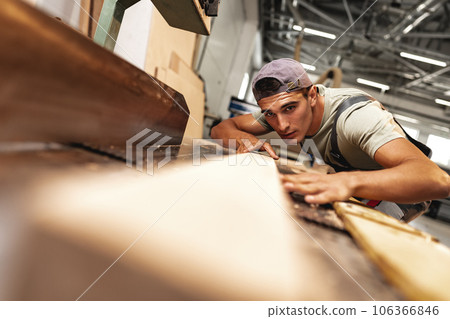 Young carpenter working on woodworking machines in the furniture factory 106366846