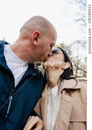 Attractive affectionate young couple standing together and kissing in the street Attractive affectionate young couple standing together and kissing in the street 106366912