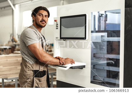 Young carpenter operating machine for wood processing at a furniture factory 106366913