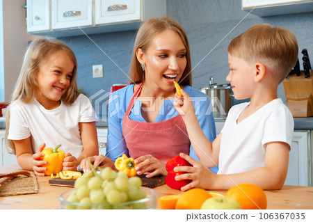 Mother cooking with her children in kitchen Mother cooking with her children in kitchen 106367035