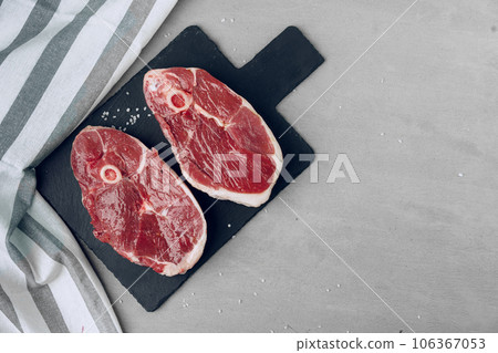 Raw rib-eye beef steak on wooden cutting board on gray background 106367053