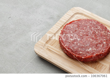 Raw beef burger patty on wooden board 106367061