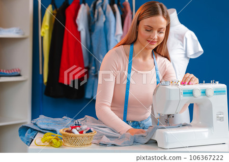 Young seamstress working on her sewing machine on textile factory 106367222