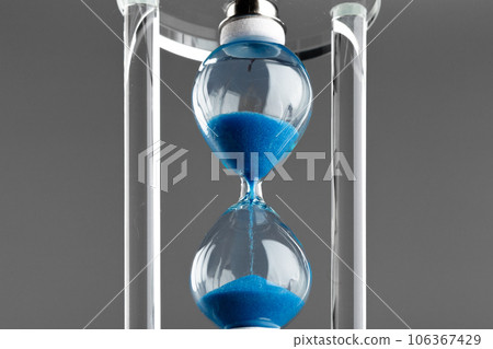 Blue hourglass on gray background close up 106367429