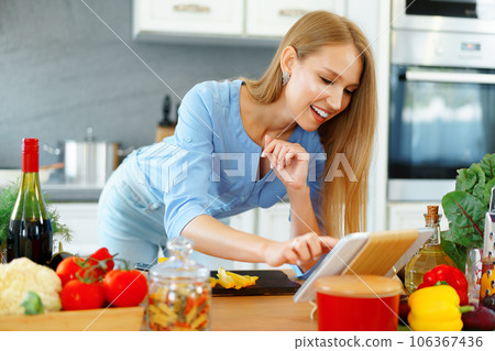Young beautiful caucasian woman cooking and using her digital tablet in kitchen Young beautiful caucasian woman cooking and using her digital tablet in kitchen 106367436