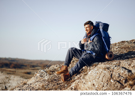 Young male hiker sitting and having a rest on a halt stop Young male hiker sitting and having a rest on a halt stop 106367476