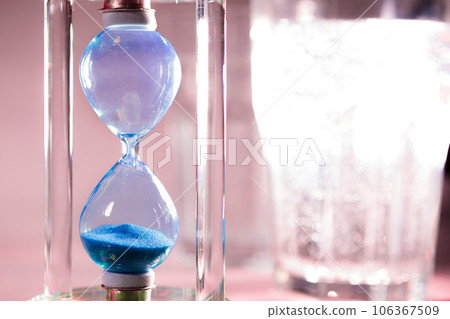 Blue hourglass on gray background close up 106367509