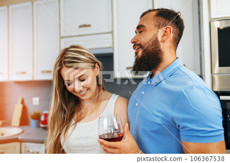 Cheerful smiling couple cooking and drinking wine in kitchen 106367538