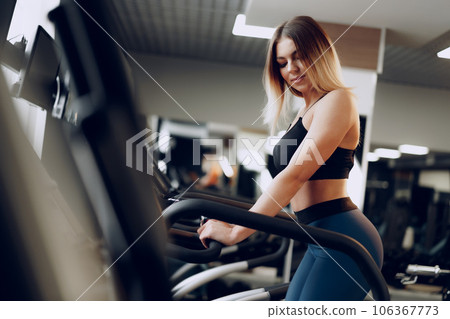 Fit curvy young blonde woman training in a cardio zone in a gym Fit curvy young blonde woman training in a cardio zone in a gym 106367773