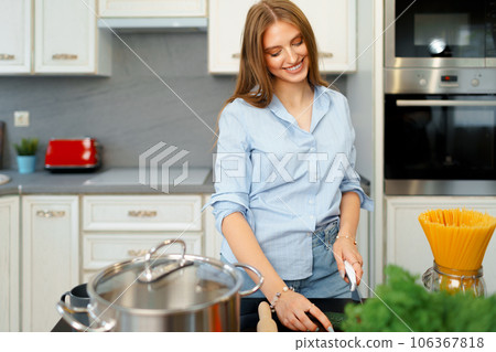Young woman cutting vegetables for salad in kitchen Young woman cutting vegetables for salad in kitchen 106367818