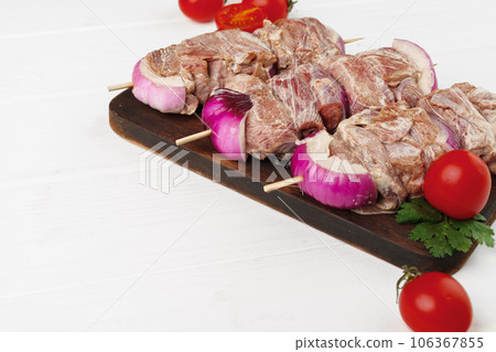 Raw marinated kebab on skewers on wooden background Raw marinated kebab on skewers on wooden background 106367855