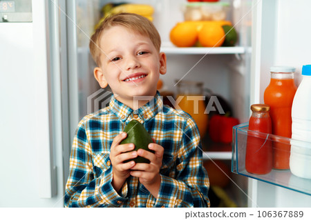 Little boy standing in front of open fridge and choosing food 106367889